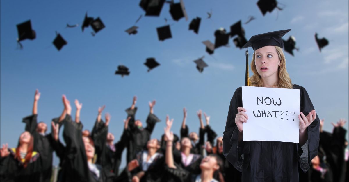 Challenging Job Market For College Grads: Blurred photo of graduates tossing their caps into the air. In the foreground stands a grad holding a sign reading, "Now What?"