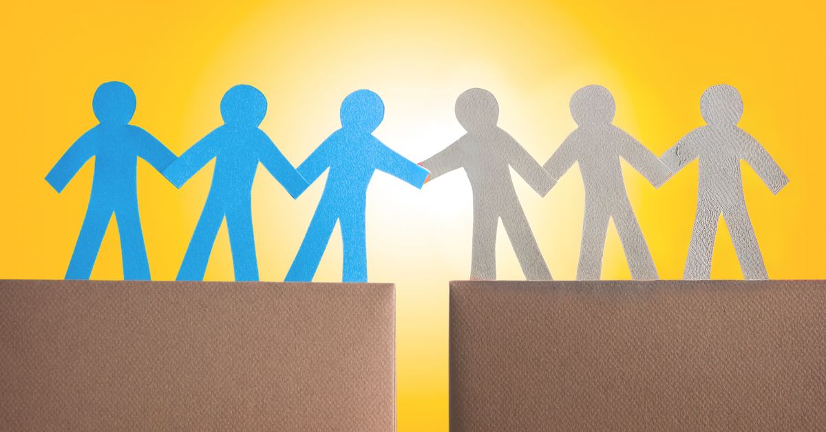 Disconnect Between Gen Z And Employers: Blue and gray silhouetted people standing on opposite sides of a chasm. The two standing closest to the gap are holding "hands."