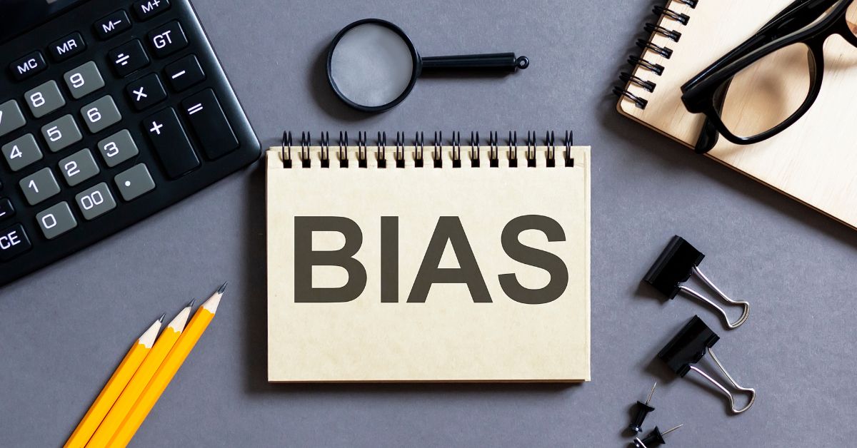 Using AI to Eliminate Bias: Desktop with various items including a notebook with the word "Bias" written on its cover.